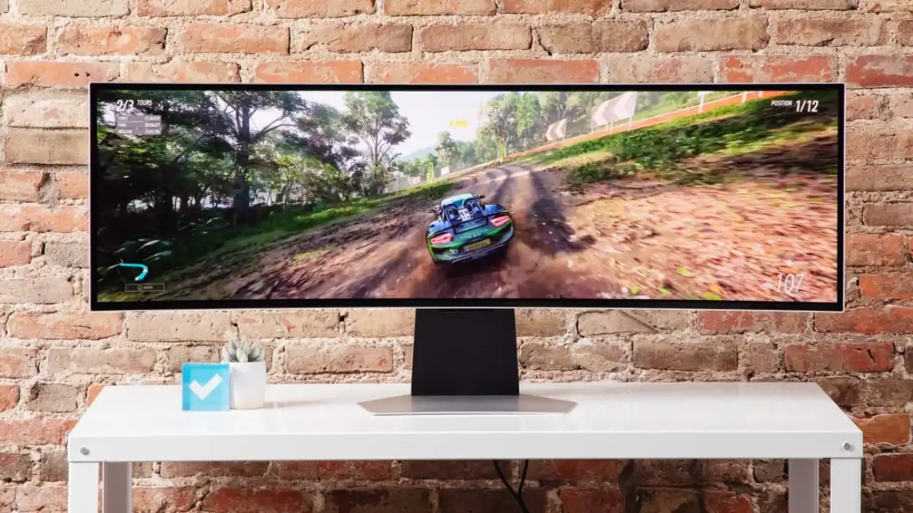 Ultrawide gaming monitor on a desk showing a racing game on a wide screen.