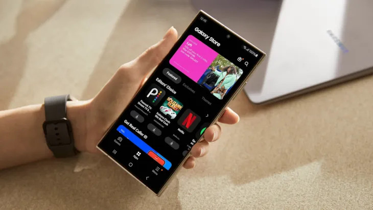 Hand holding a smartphone displaying the Samsung Galaxy Store interface