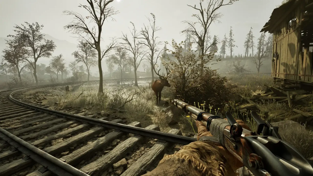 First-person view aiming a rifle at an elk standing near railway tracks in a foggy clearing in Winter Survival.