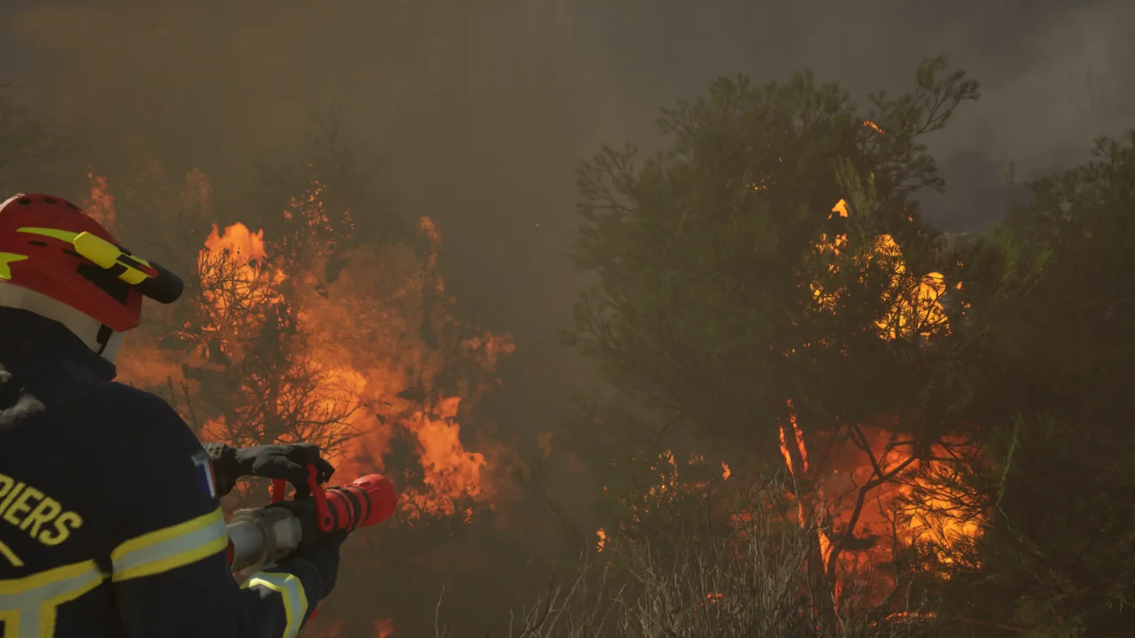 Firefighter aiming a hose at burning trees in Rescue Ops: Wildfire.