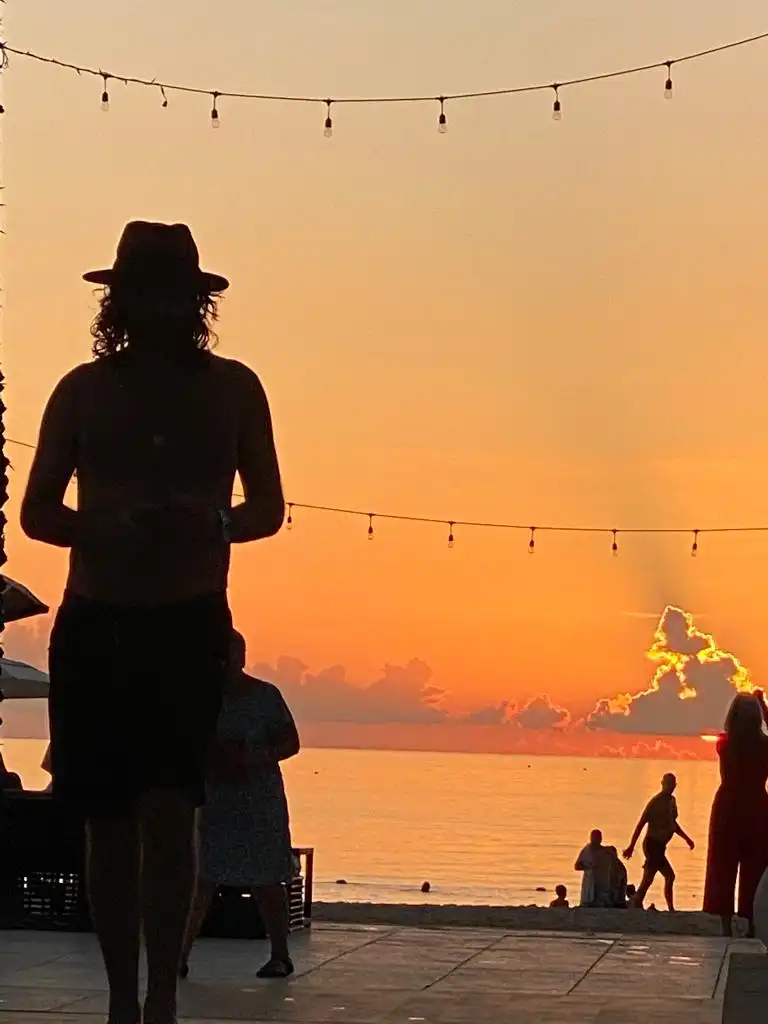 David Priestman standing in silhouette beside the sea during sunset in Koh Samui, Thailand.