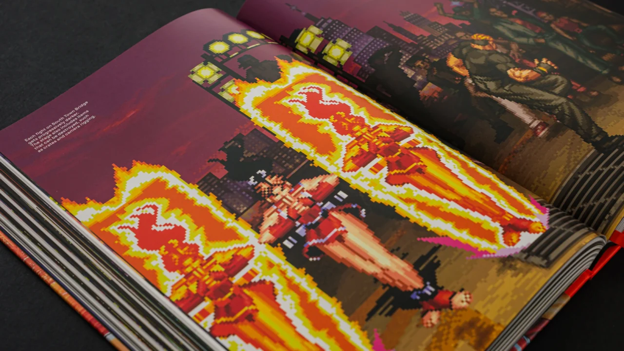 Open Fatal Fury Ultimate History book showing a fiery pixel-art battle across two pages