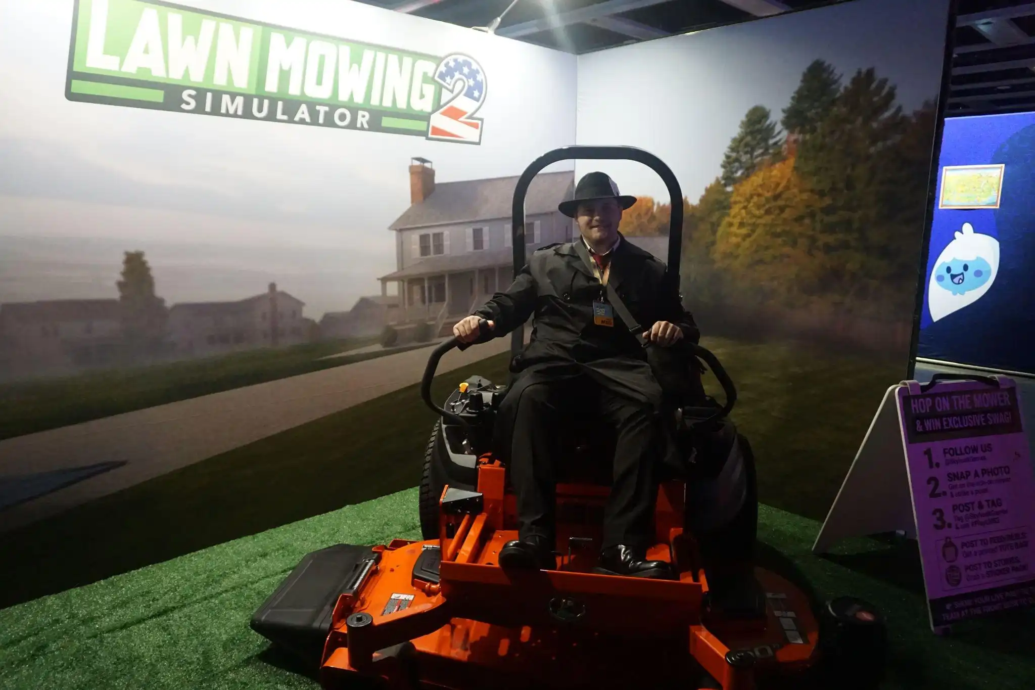 Jake Boyette sitting on a rideable mower at the Lawn Mowing Simulator 2 booth during PAX West 2026