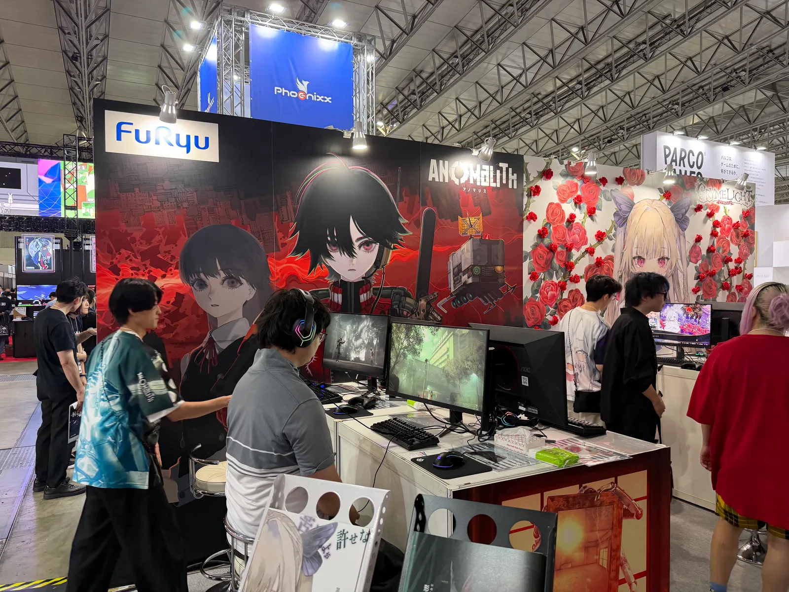 FuRyu's ANOMALITH booth at Tokyo Game Show, showing promotional artwork and PC demo stations.